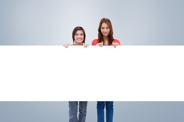 Smiling young women proudly holding a blank poster
