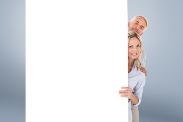 Composite image of happy couple showing large poster