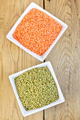 Lentils red and green in white bowls on board