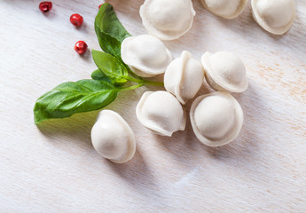 Tortellini and vegetables on white wooden background
