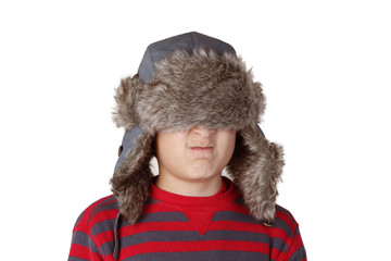 Boy in furry hat puloling funny faces on white background