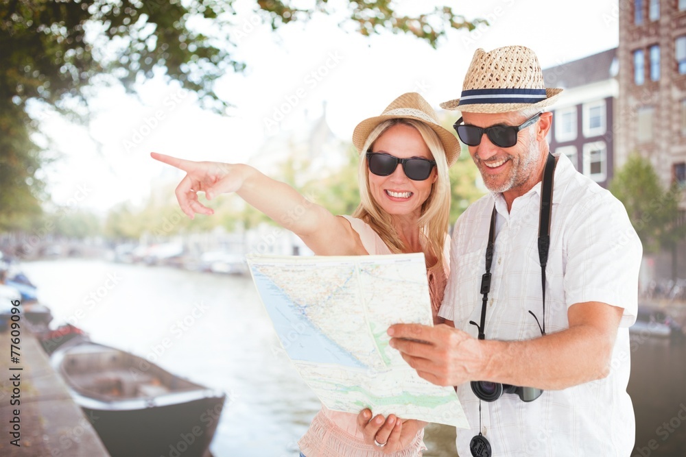 Aufkleber Composite image of happy tourist couple using map and pointing