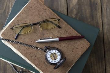 An antique pocket watch, glasses and books