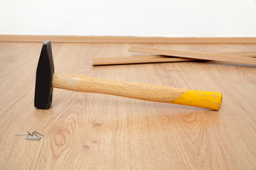Laminate flooring of room, hammer batten and nails at floor