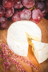 Smelly blue cheese on a wooden rustic table with grape