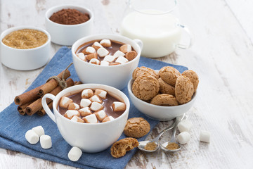 cocoa with marshmallows and almond cookies on white wooden table