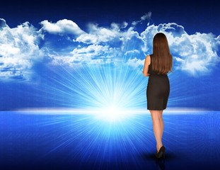 Fototapeta na wymiar Businesswoman standing against blue landscape with rising sun