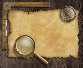 vintage nautical compass and loupe on table with treasure map