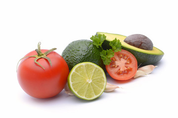 Fresh avocado surrounded by  tomato, garlic and lime on white background