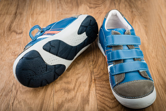 Pair of blue sneakers in children size on wooden background