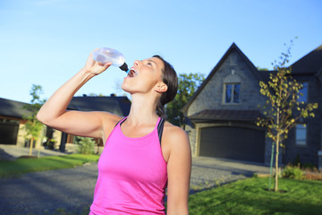 A woman jogging in a urban place with house in the background