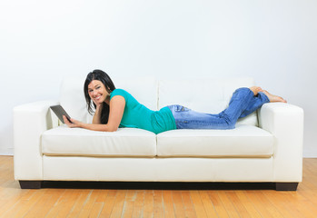 Fototapeta na wymiar Young woman using electronic tablet sitting on sofa