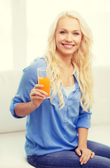 smiling woman with glass of orange juice at home