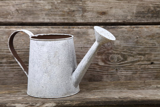 Watering can on a wooden background