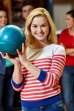 happy young woman holding ball in bowling club