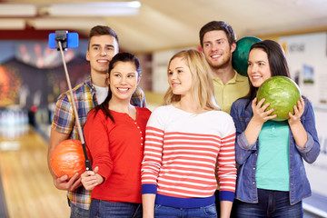 happy friends taking selfie in bowling club