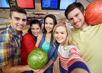 happy friends taking selfie in bowling club