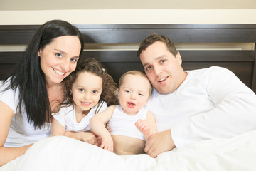 Fototapeta premium Young family resting together in parent's bed