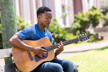 young african college student playing guitar
