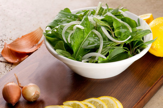 Rucola salad leaves with ingredients on a wooden plate