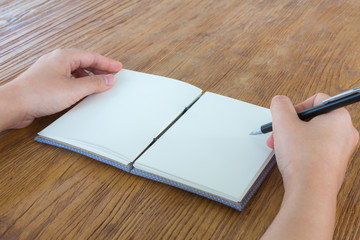 Hands with pencil and book on wood table
