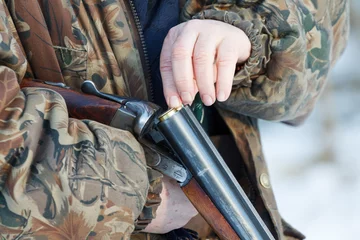 Poster jager laadt zijn oude dubbelloops zij aan zij jachtgeweer © joppo