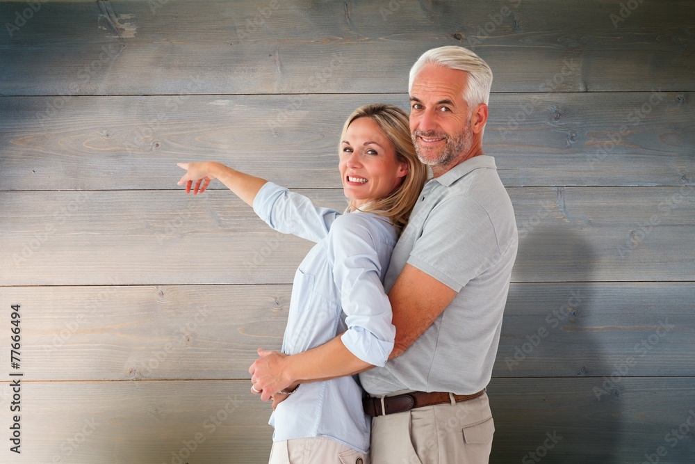 Aufkleber Composite image of happy couple smiling at camera and pointing