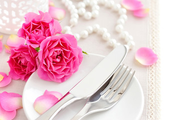 Romantic table setting with pink roses on a linen napkin