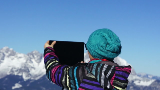 Woman taking photo with digital tablet in the mountains