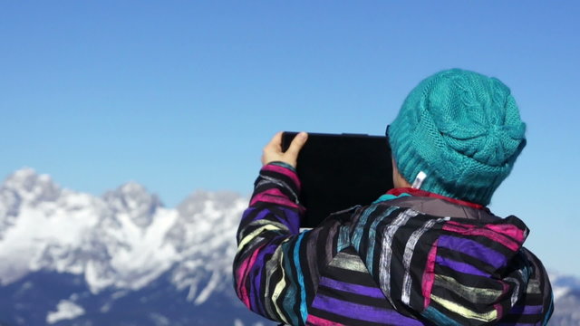 Woman taking photo with digital tablet in the mountains