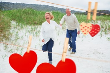 Composite image of cheerful senior couple running at beach