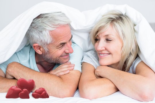 Composite image of closeup of a mature couple lying in bed