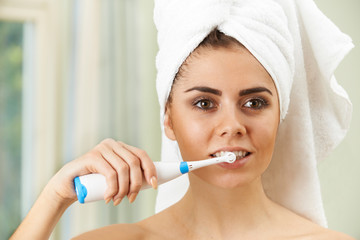 Woman Brushing Teeth With Electric Toothbrush In Bathroom