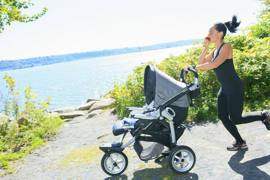 A Young mother jogging with a baby buggy