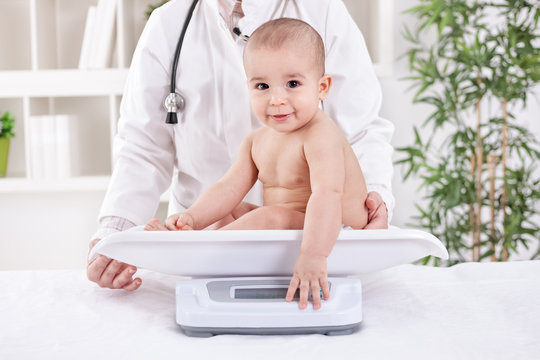 Adorable little baby child with pediatrician, weight measuring