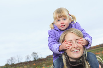 Fototapeta na wymiar Mother giving daughter piggyback ride in autumn woodland