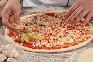 Manos preparando pizza.