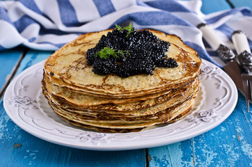 A stack of pancakes with black caviar