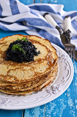A stack of pancakes with black caviar