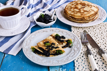 A stack of pancakes with black caviar