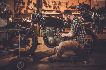 Fototapeta na wymiar Man and vintage style cafe-racer motorcycle in custom garage