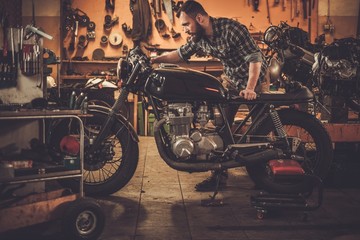 Man and vintage style cafe-racer motorcycle in garage