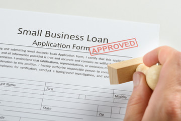 Person Hand Holding Rubber Stamp Over Loan Application