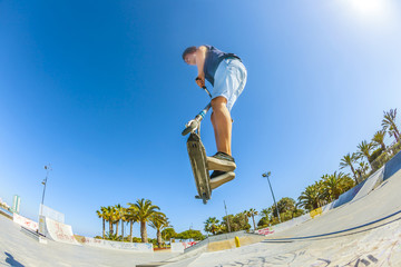 boy jumps with his scooter over a ramp
