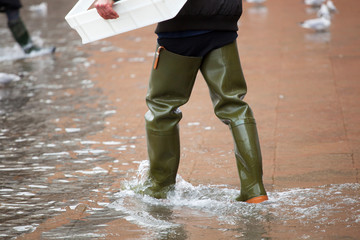 Fototapeta premium Close Up of legs with boots due to the high water in Venice.