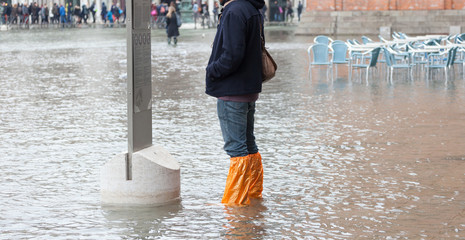 Close Up of legs with boots due to the high water in Venice.