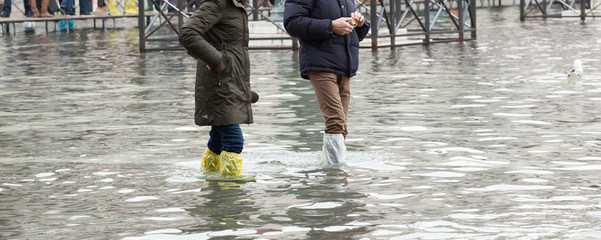 Close Up of legs with boots due to the high water in Venice.