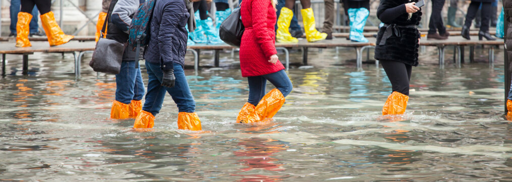 Fototapeta Close Up of legs with boots due to the high water in Venice.