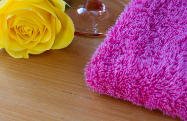 Obraz na płótnie Canvas Yellow rose with a wine glass and a pink towel