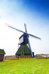 Fototapeta na wymiar Rotating wooden windmill on farm field in Holland